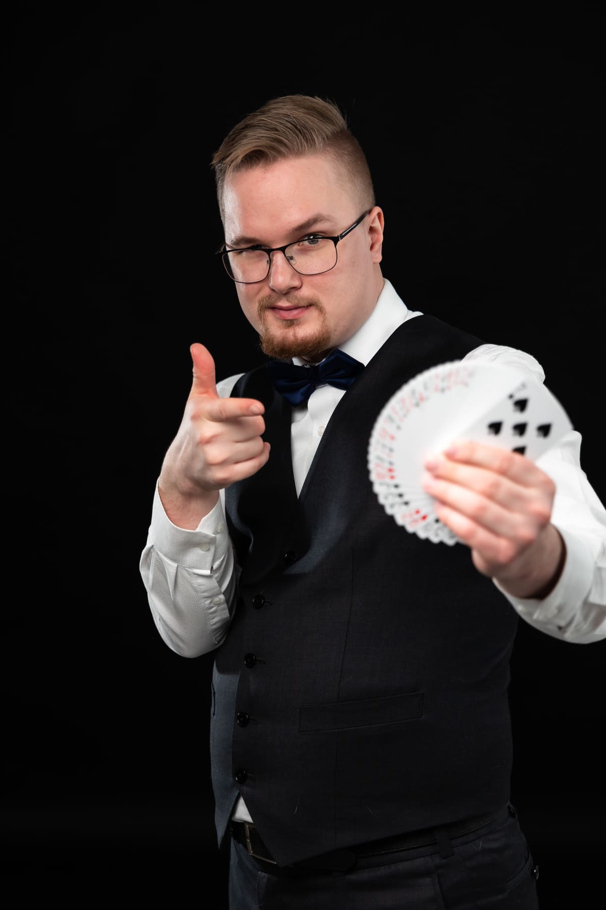 Taavi Saarva points at the camera while holding a fan of cards.